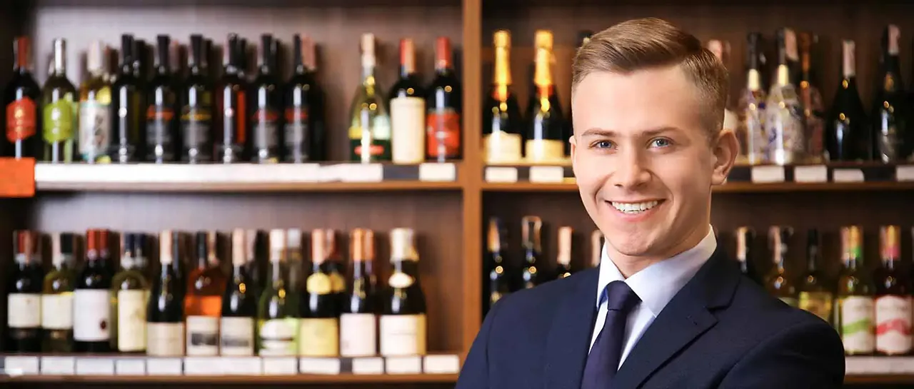 Male bartender in front of wine shelf